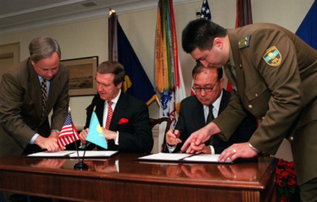 Secretary of Defense William S. Cohen (seated left) and Kazakhstan's Minister of Defense Lt. Gen. Sat Takpakbayev (seated right) sign a Defense Cooperation Plan for 2000 at the conclusion of their meetings at the Pentagon on Dec. 17, 1999. 