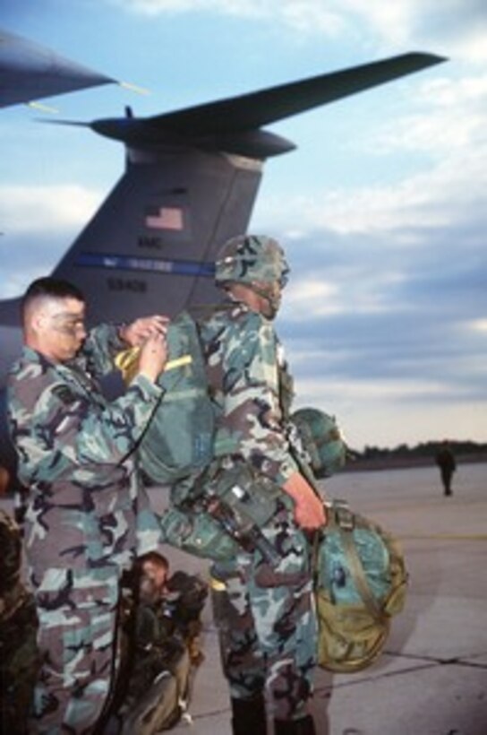 U.S. Army Sgt. William Bravo (left), 307th Forward Support Battalion, checks Sgt. 1st Class Bruce Smith's parachute prior to the soldiers loading into a U.S. Air Force C-141 Starlifter at Pope Air Force Base, N.C., on Jan. 20, 1999. The soldiers are participating in air drop as part of Large Package Week, a joint exercise involving Air Force aircraft operating from Pope and soldiers of the U.S. Army's 82nd Airborne, at Fort Bragg, N.C. 