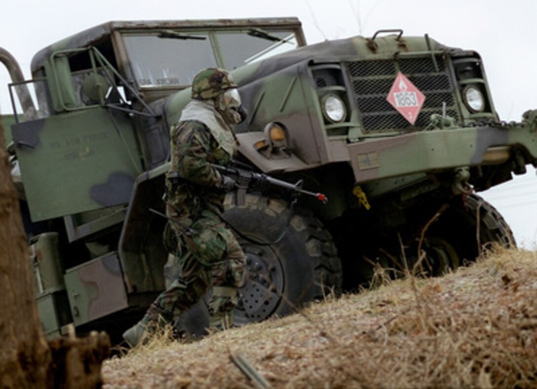 A member of the U.S. Air Force 51st Security Forces Squadron moves up a hillside as he conducts a search through an industrial facility on Jan. 7, 1999, as part of combat employment readiness exercise Beverly Midnight 99-1, at Osan Air Base, Republic of Korea. The exercise is designed to test people's ability to carry out their wartime tasking, air base ground defense, and ability to recover after attacks. During the exercise, personnel quickly become accustomed to working and resting while wearing the Ground Crew Ensemble and its MCU-2P chemical/biological protective mask to protect themselves from chemical warfare agents. 