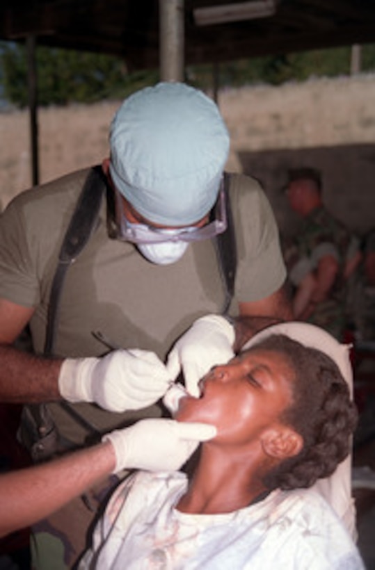 Petty Officer 2nd Class Joseph Marcus takes care of a filling in a Haitian woman's tooth during a routine dental visit at humanitarian assistance site Saint Terese in Haiti on Dec. 15, 1998. Sailors from the 2nd Medical Battalion and Marines from 3rd Battalion, 2nd Marines, Kilo Company, are setting up temporary humanitarian assistance sites to provide medical and dental attention to the Haitian people. Troops of U.S. Support Group Haiti are stationed in Port-au-Prince, Haiti, in support of Operation Uphold Democracy. Marcus is a Navy hospital corpsman with the 2nd Medical Battalion. 