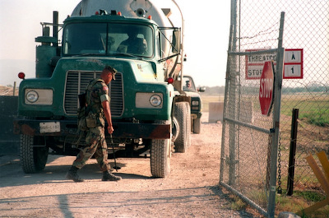 U.S. Marine Corps Lance Cpl. Timothy Marino uses a mirror to inspect the under carriage of a truck before admitting it into Camp Fairwinds in Port-au-Prince, Haiti, on Dec. 15, 1998. Troops of the U.S. Support Group Haiti are deployed to Camp Fairwinds in support of Operation Uphold Democracy. The Group is setting up temporary humanitarian assistance sites to provide medical and dental attention to the Haitian people and rebuilding schools and roads throughout Haiti. Marino is attached to the 3rd Battalion, 2nd Marines. 