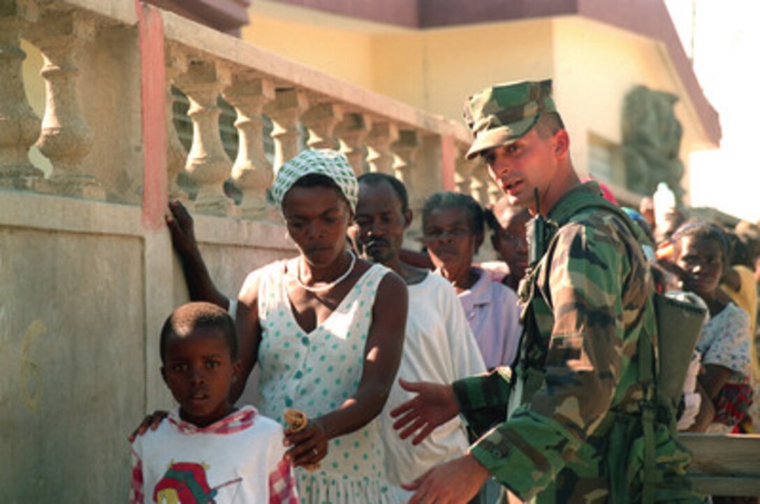 Cpl. Shawn Walsh, U.S. Marine Corps, allows a young Haitian mother and son through a security checkpoint at humanitarian assistance site Saint Terese in Haiti on Dec. 15, 1998. Sailors from the 2nd Medical Battalion and Marines from 3rd Battalion, 2nd Marines, Kilo Company, are setting up temporary humanitarian assistance sites to provide medical and dental attention to the Haitian people. Troops of U.S. Support Group Haiti are stationed in Port-au-Prince, Haiti, in support of Operation Uphold Democracy. 