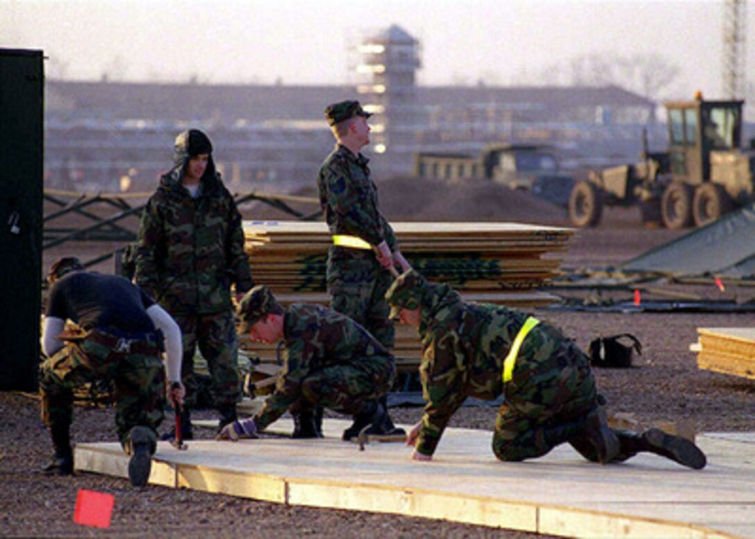 Engineers from the U.S. Air Force 786th Civil Engineering Squadron, Ramstein Air Base, Germany, construct a plywood floor for a tent at Aviano Air Base, Italy, on Feb. 20, 1999. U.S. aircraft and support personnel are deploying to their forward staging bases in Europe for potential NATO air operations. 