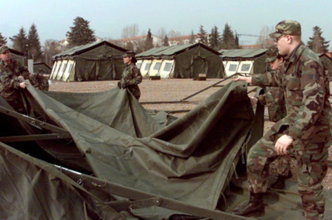 U.S. Air Force civil engineering and services people from RAF Lakenheath, United Kingdom, and Ramstein Air Base, Germany, help set up a temperature-controlled tent in the growing tent city at Aviano Air Base, Italy, on Feb. 20, 1999. U.S. aircraft and support personnel are deploying to their forward staging bases in Europe for potential NATO air operations. 