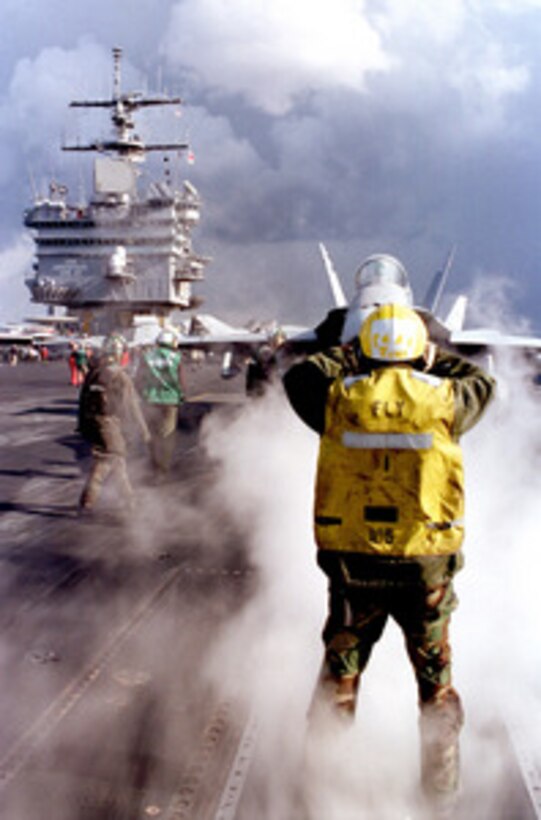 An F/A- 18 Hornet is directed by a yellow shirt to the forward port catapult on the flight deck of the of USS Enterprise (CVN 65) as the ship conducts flight operations in the Mediterranean Sea on Feb. 11, 1999. 