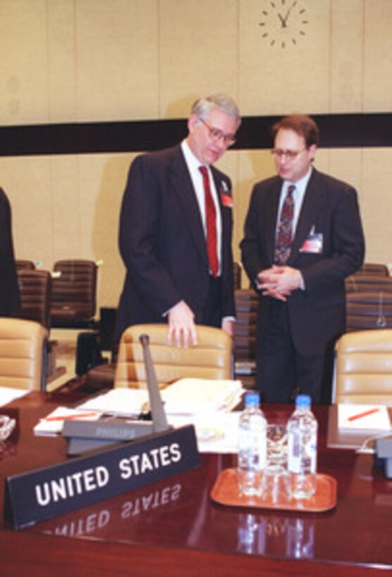 Deputy Secretary of Defense John J. Hamre (left) confers with U.S. Ambassador to NATO Alexander (Sandy) Vershbow before the start of the Euro-Atlantic Partnership Council meeting at NATO headquarters, Brussels, Belgium, on Dec. 18, 1998. Hamre replaced Secretary of Defense William Cohen at the December NATO Defense Ministerial. Cohen elected to remain in Washington to oversee the U.S.--British bombing campaign against Iraq, which began on Dec. 16, 1998. 