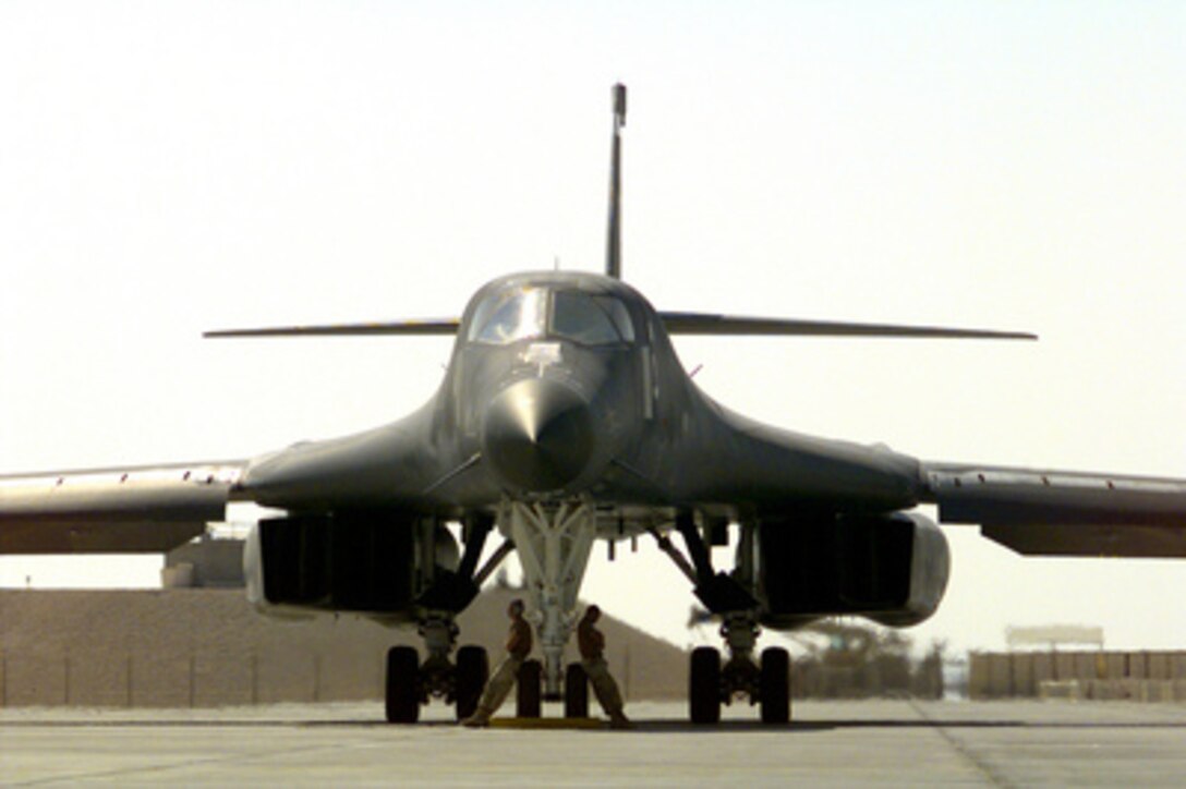Two ground crew members take advantage of the shade created by a U.S. Air Force B-1B Lancer bomber as it goes through a pre-flight operations check at an air base in the Persian Gulf region on Dec. 14, 1998. The Lancer and its crew are deployed to the Persian Gulf from Ellsworth Air Force Base, S.D. 