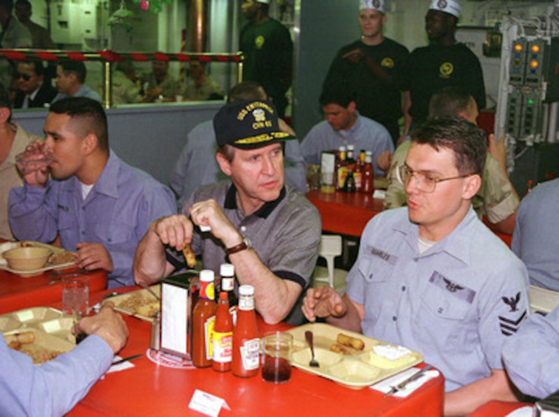 Secretary of Defense William S. Cohen (center) joins crew members of the USS Enterprise (CVN 65) on the enlisted mess decks for lunch on Dec. 23, 1998. Cohen congratulated and commended the crew for their professionalism during Operation Desert Fox. Enterprise and its embarked Carrier Air Wing 3 are deployed to the Persian Gulf in support of Operation Southern Watch, which is the U.S. and coalition enforcement of the no-fly-zone over Southern Iraq. 