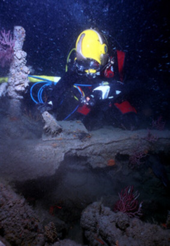 U.S. Navy Cmdr. Philip G. Beierl inspects an artifact on the sunken U.S. Civil War ship USS Monitor 240 feet below the ocean's surface on June 23, 1999. Beierl is diving from the USS Grasp (ARS 51) in waters sixteen miles off Cape Hatteras, N.C. The battle between the USS Monitor and the CSS Virginia, formerly the USS Merrimack, on March 9, 1862, at Hampton Roads, Va., was the first battle fought by iron armored vessels during the civil war. Beierl is the commanding officer of Mobile Diving and Salvage Unit Two. 