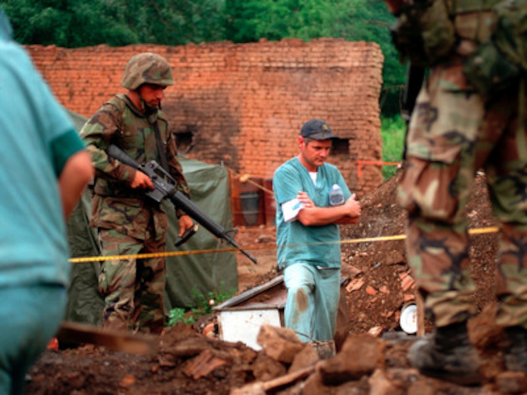 U.S. Marines provide security as members of the Royal Canadian Mounted Police Forensics Team investigate a grave site in a village in Kosovo on July 1, 1999. Elements of the 26th Marine Expeditionary Unit are deployed from ships of the USS Kearsarge Amphibious Ready Group as an enabling force for KFOR. KFOR is the NATO-led, international military force which will deploy into Kosovo on a peacekeeping mission known as Operation Joint Guardian. KFOR will ultimately consist of over 50,000 troops from more than 24 contributing nations, including NATO member-states, Partnership for Peace nations and others. 