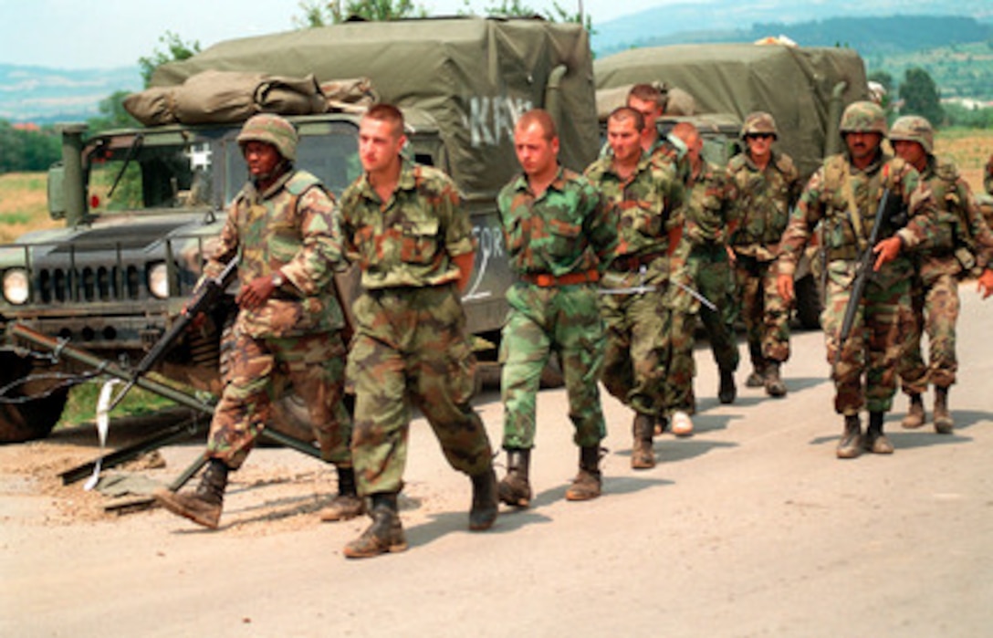 U.S. Marines from the 26th Marine Expeditionary Unit escort Serbian detainees to the Kosovo-Serbian border where they will be released to Serbian authorities on July 3, 1999. Elements of the 26th Marine Expeditionary Unit are deployed from ships of the USS Kearsarge Amphibious Ready Group as an enabling force for KFOR. KFOR is the NATO-led, international military force which will deploy into Kosovo on a peacekeeping mission known as Operation Joint Guardian. KFOR will ultimately consist of over 50,000 troops from more than 24 contributing nations, including NATO member-states, Partnership for Peace nations and others. 