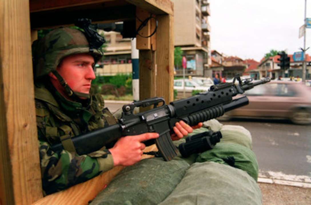 Cpl. DeChristopher Curtin mans a sand-bagged position in front of the Lima company command post in Gnjilane, Kosovo, on July 5, 1999. Elements of the 26th Marine Expeditionary Unit are deployed from ships of the USS Kearsarge Amphibious Ready Group as an enabling force for KFOR. KFOR is the NATO-led, international military force which will deploy into Kosovo on a peacekeeping mission known as Operation Joint Guardian. KFOR will ultimately consist of over 50,000 troops from more than 24 contributing nations, including NATO member-states, Partnership for Peace nations and others. Curtin, from Andersonville, Tenn., is attached to Lima Company, 3rd Battalion, 8th Marine Regiment. 