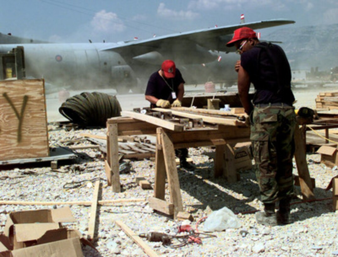Red Horse engineers Staff Sgt. Joseph Ingram (left) and Senior Airman Dennis Maldonado work alongside the ramp at Rinas Airport in Tiranë, Albania, on July 2, 1999, building concrete forms for a new taxiway at the airport. The airport will become one of the logistical hubs for KFOR. KFOR is the NATO-led, international military force which is deploying into Kosovo on the peacekeeping mission known as Operation Joint Guardian. KFOR will ultimately consist of over 50,000 troops from more than 24 contributing nations, including NATO member-states, Partnership for Peace nations and others. The U.S. Air Force civil engineers from the 820th Red Horse Squadron, Nellis Air Force Base, Nev., have been tasked to construct the concrete taxiway which will be 15 inches thick, 75 feet wide and 1,016 feet long. 
