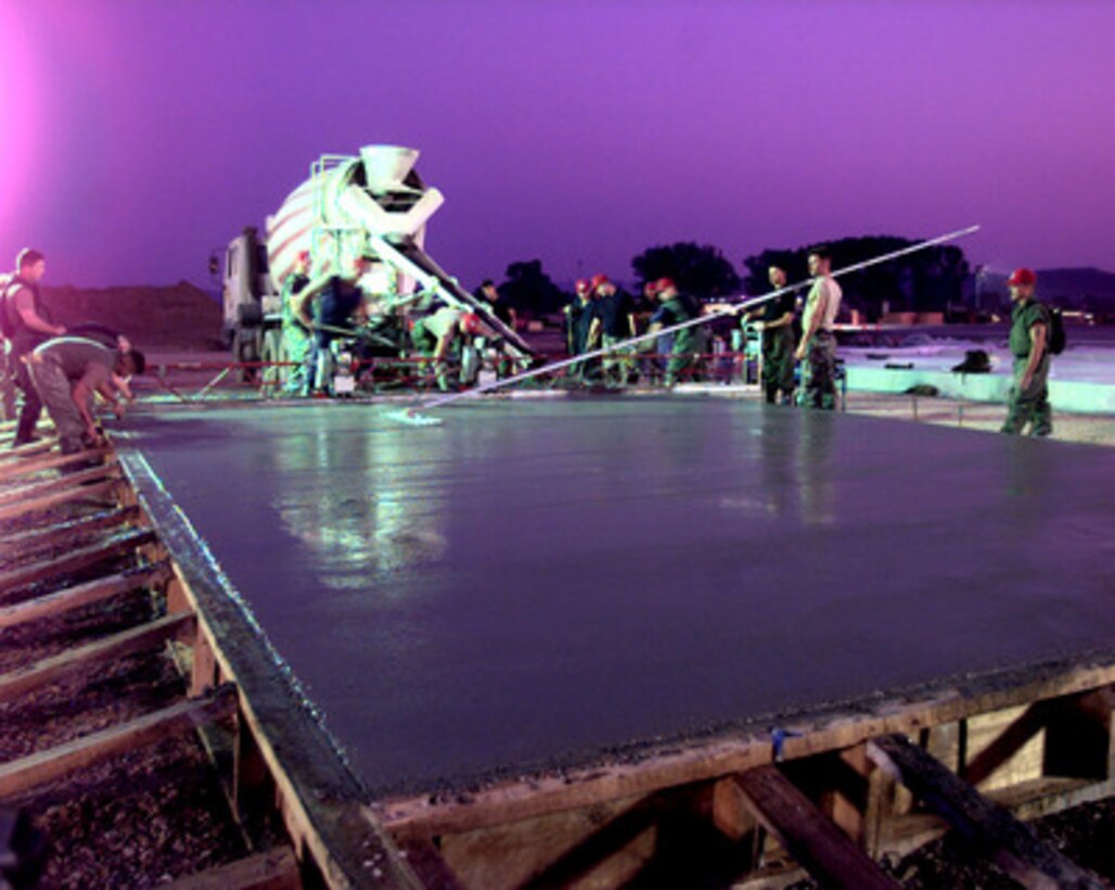 Red Horse engineers work around the clock at Rinas Airport in Tiranë, Albania, as they pour and smooth concrete for a new taxiway at the airport on July 2, 1999. The airport will become one of the logistical hubs for KFOR. KFOR is the NATO-led, international military force which is deploying into Kosovo on the peacekeeping mission known as Operation Joint Guardian. KFOR will ultimately consist of over 50,000 troops from more than 24 contributing nations, including NATO member-states, Partnership for Peace nations and others. The U.S. Air Force civil engineers from the 820th Red Horse Squadron, Nellis Air Force Base, Nev., have been tasked to construct the concrete taxiway which will be 15 inches thick, 75 feet wide and 1,016 feet long. 