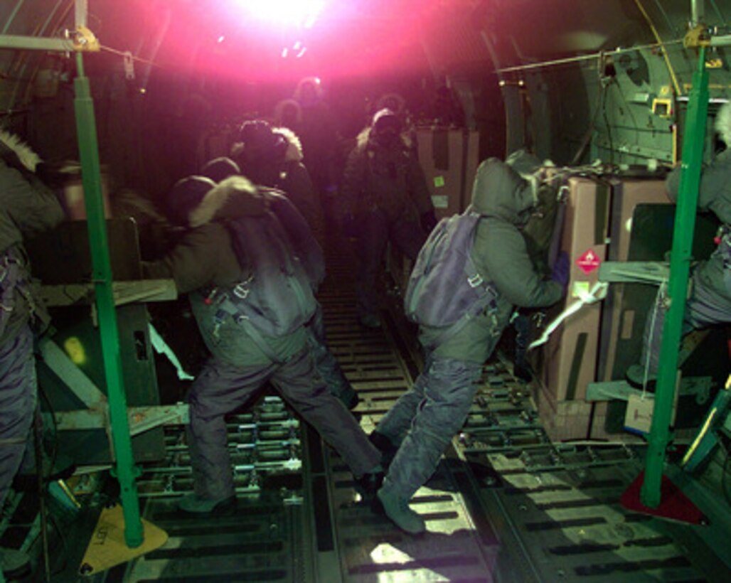 U.S. Air Force loadmasters brave minus-100 degree temperatures to push cargo bundles out the troop doors of a U.S. Air Force C-141 Starlifter into the Antartic night over Amundsen-Scott South Pole Station on July 12, 1999. The Air Force crew is conducting a humanitarian, mid-winter air drop mission to Amundsen-Scott South Pole Station operated by the National Science Foundation. Two of the air drop bundles contain critical medical supplies needed for a 47-year-old American woman who discovered a lump in her breast. Four bundles of mail and food were also dropped. The loadmasters are from the 62nd Air Wing, McChord Air Force Base, Wash. 