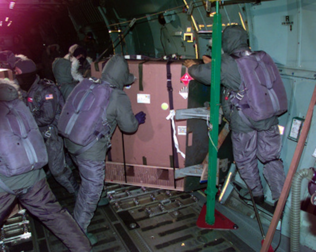 U.S. Air Force loadmasters brave minus-100 degree temperatures to push cargo bundles out the troop doors of a U.S. Air Force C-141 Starlifter into the Antartic night over Amundsen-Scott South Pole Station on July 12, 1999. The Air Force crew is conducting a humanitarian, mid-winter air drop mission to Amundsen-Scott South Pole Station operated by the National Science Foundation. Two of the air drop bundles contain critical medical supplies needed for a 47-year-old American woman who discovered a lump in her breast. Four bundles of mail and food were also dropped. The loadmasters are from the 62nd Air Wing, McChord Air Force Base, Wash. 