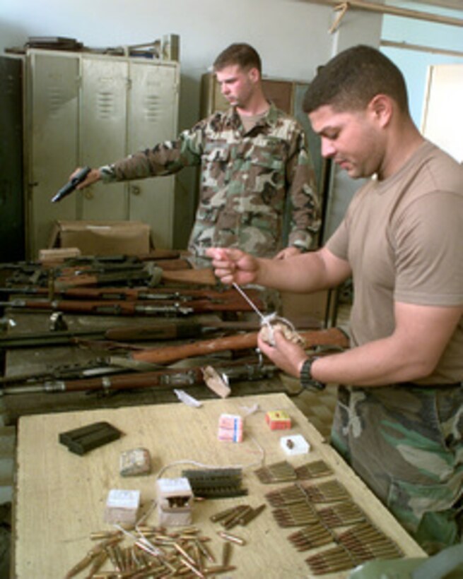 U.S. Army Staff Sgts. Rafael Rivera (right) and Lance Casey clear and safe weapons and ammunition that were confiscated on July 5, 1999 in Vitina, Kosovo. Rivera and Casey are attached to the 82nd Airborne Division and are deployed as part of KFOR. KFOR is the NATO-led, international military force in Kosovo on the peacekeeping mission known as Operation Joint Guardian. 