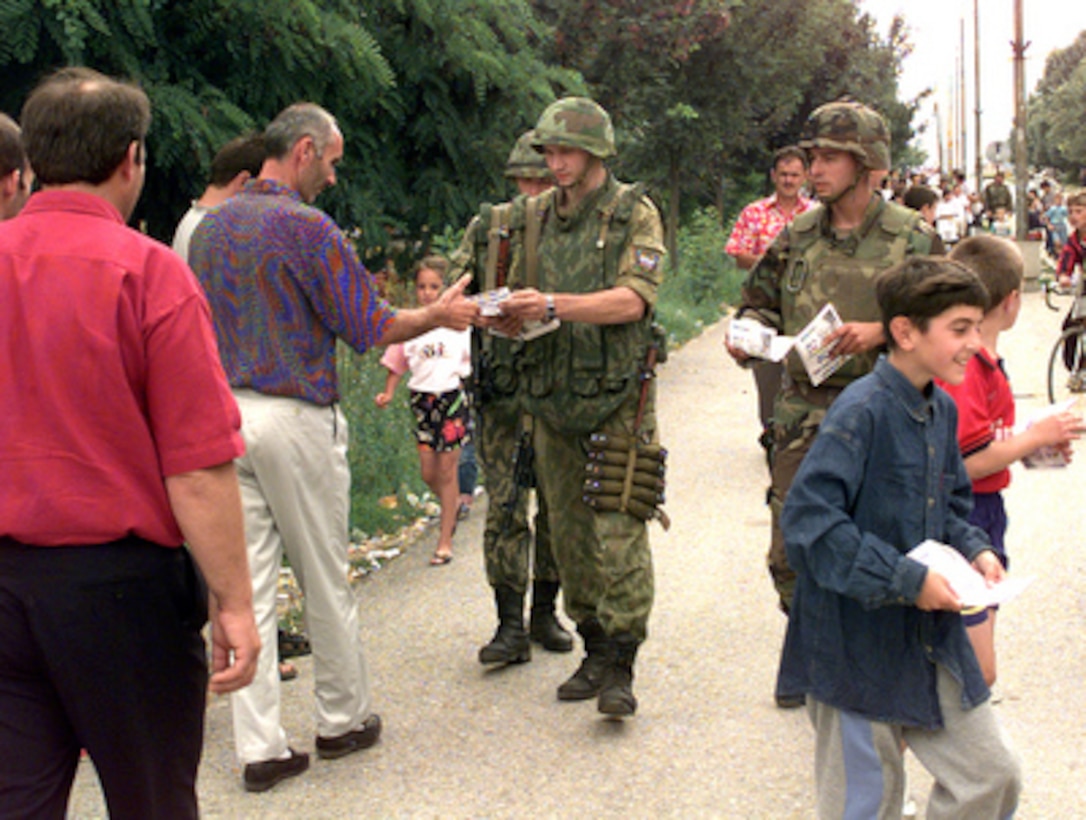 American and Russian soldiers pass out flyers to the citizens of Kamenica, Kosovo, on July 15, 1999. The flyers are asking the citizens to give a thumbs up to the KFOR soldier as a sign of peace. American soldiers from the 9th Psychological Battalion, Fort Bragg, N.C., are working side-by-side with the Russian soldiers from the 76th Airborne Division. KFOR is the NATO-led, international military force deployed to Kosovo on the peacekeeping mission known as Operation Joint Guardian. 