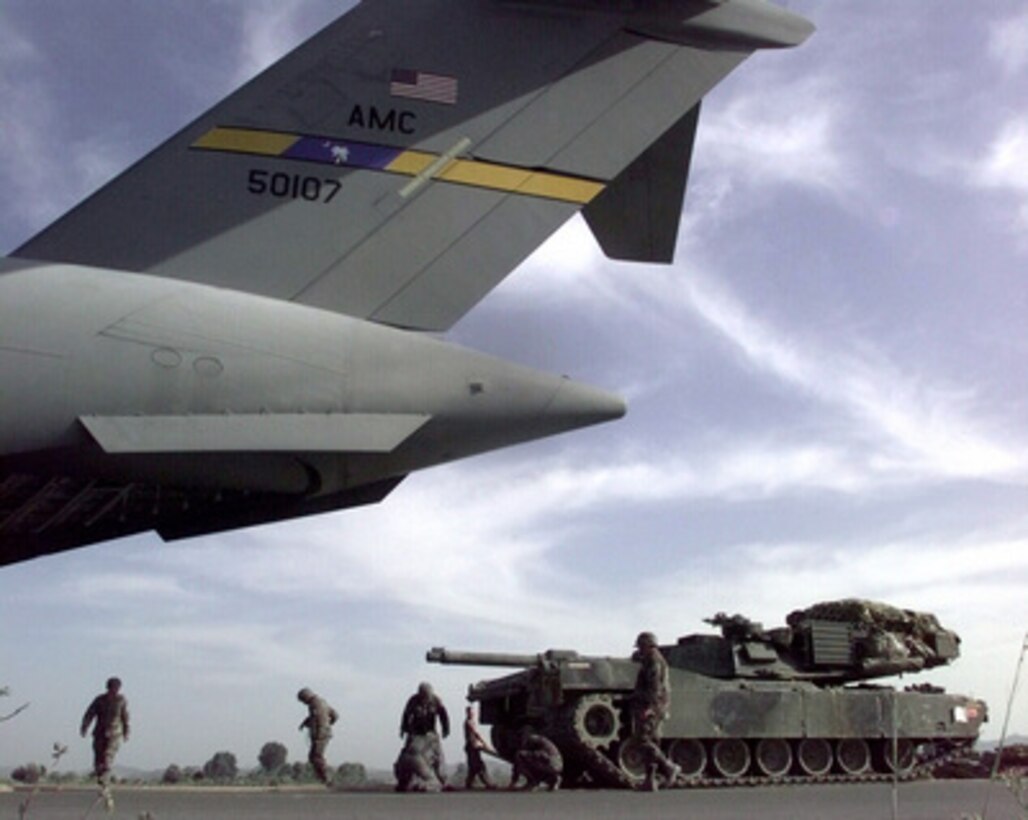 Soldiers and airmen lay down a track of plywood as they load a U.S. Army M-1A1 Abrams tank into a U.S. Air Force C-17A Globemaster III at the Rinas, Albania, airport on June 10, 1999. The tank will be transported to Skopje, Macedonia, to join KFOR. KFOR is the NATO-led, international military force which will deploy into Kosovo on a peacekeeping mission known as Operation Joint Guardian. KFOR will ultimately consist of over 50,000 troops from more than 24 contributing nations, including NATO member-states, Partnership for Peace nations and others. 