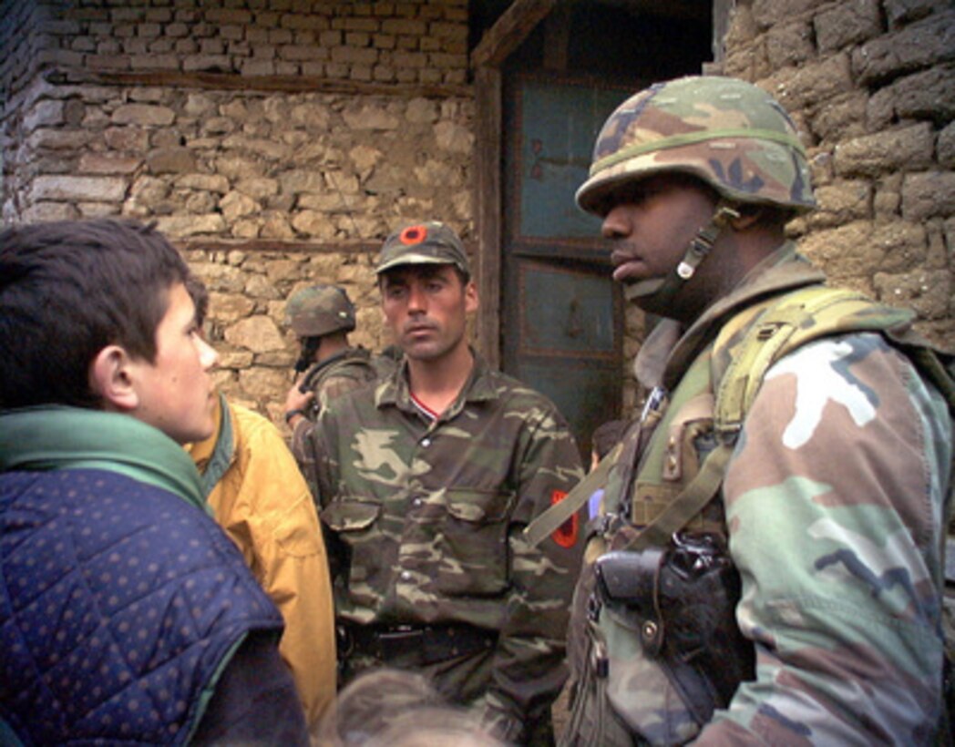 U.S. Marine Corps 1st Lt. Julian Gudger, (right) uses a local Albanian translator (left) while discussing the location of a possible Serbian sniper with a Kosovo Liberation Army soldier in Cernica, Kosovo, on June 23, 1999. Elements of the 26th Marine Expeditionary Unit are deployed from ships of the USS Kearsarge Amphibious Ready Group as an enabling force for KFOR. KFOR is the NATO-led, international military force which will deploy into Kosovo on a peacekeeping mission known as Operation Joint Guardian. 