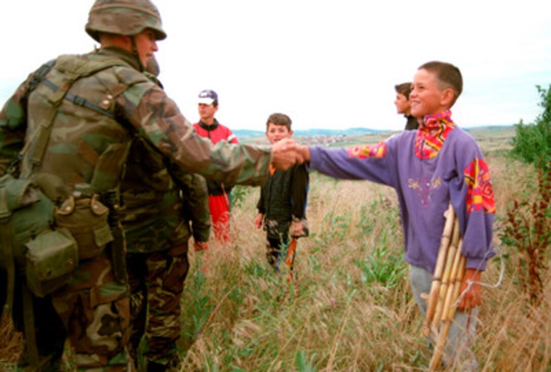 U.S. Marines greet local boys near the perimeter of Camp Montieth near Gnjilane, Kosovo, on June 25, 1999. Elements of the 26th Marine Expeditionary Unit are deployed from ships of the USS Kearsarge Amphibious Ready Group as an enabling force for KFOR. KFOR is the NATO-led, international military force which will deploy into Kosovo on a peacekeeping mission known as Operation Joint Guardian. KFOR will ultimately consist of over 50,000 troops from more than 24 contributing nations, including NATO member-states, Partnership for Peace nations and others. 