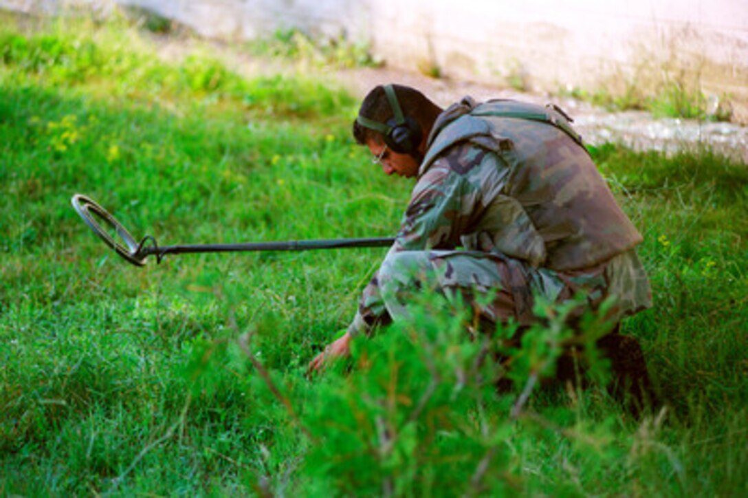 A U.S. Marine from the 2nd Combat Engineer Battalion lifts his mine detecting equipment as he probes for mines in a Kosovo school yard on June 26, 1999. Elements of the 26th Marine Expeditionary Unit are deployed from ships of the USS Kearsarge Amphibious Ready Group as an enabling force for KFOR. KFOR is the NATO-led, international military force which will deploy into Kosovo on a peacekeeping mission known as Operation Joint Guardian. KFOR will ultimately consist of over 50,000 troops from more than 24 contributing nations, including NATO member-states, Partnership for Peace nations and others. 