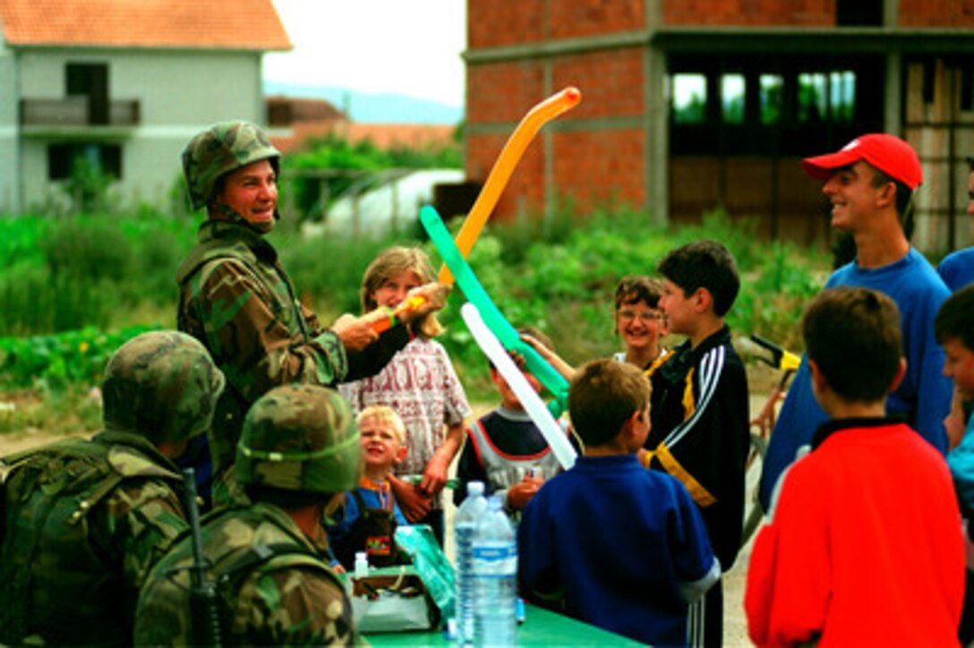 Petty Officer 1st Class Marty Satterfield, U.S. Navy, entertains local Serbian youths with balloon animals in Kosovo on June 26, 1999. Satterfield is a Navy hospital corpsman attached to the 26th Marine Expeditionary Unit. Elements of the 26th deployed from ships of the USS Kearsarge Amphibious Ready Group as an enabling force for KFOR. KFOR is the NATO-led, international military force which will deploy into Kosovo on a peacekeeping mission known as Operation Joint Guardian. KFOR will ultimately consist of over 50,000 troops from more than 24 contributing nations, including NATO member-states, Partnership for Peace nations and others. Satterfield, from Ardmore, Ala., is a professional clown in his off duty time. 