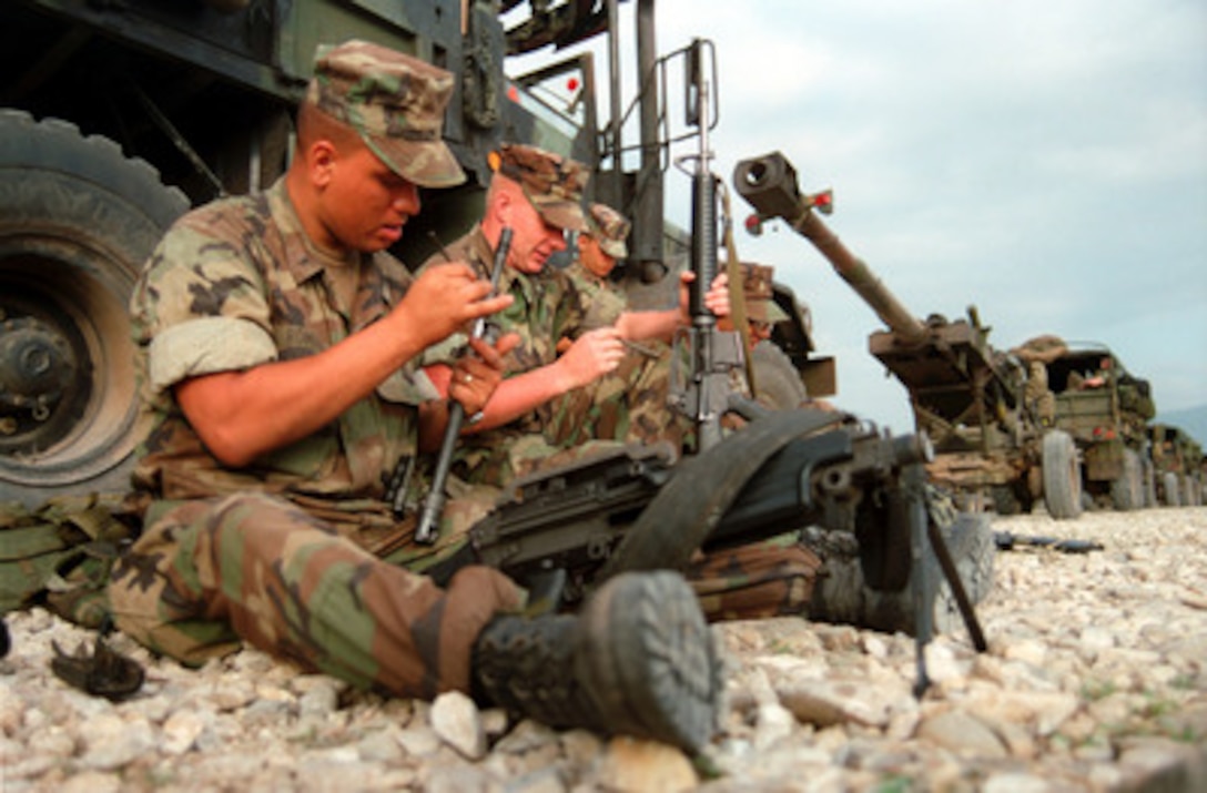 Marines from Lima Battery, 3rd Battalion, 10th Marine Regiment clean their weapons as they wait in a vehicle convoy in Kosovo on June 26, 1999. Elements of the 26th Marine Expeditionary Unit are deployed from ships of the USS Kearsarge Amphibious Ready Group as an enabling force for KFOR. KFOR is the NATO-led, international military force which will deploy into Kosovo on a peacekeeping mission known as Operation Joint Guardian. KFOR will ultimately consist of over 50,000 troops from more than 24 contributing nations, including NATO member-states, Partnership for Peace nations and others. 