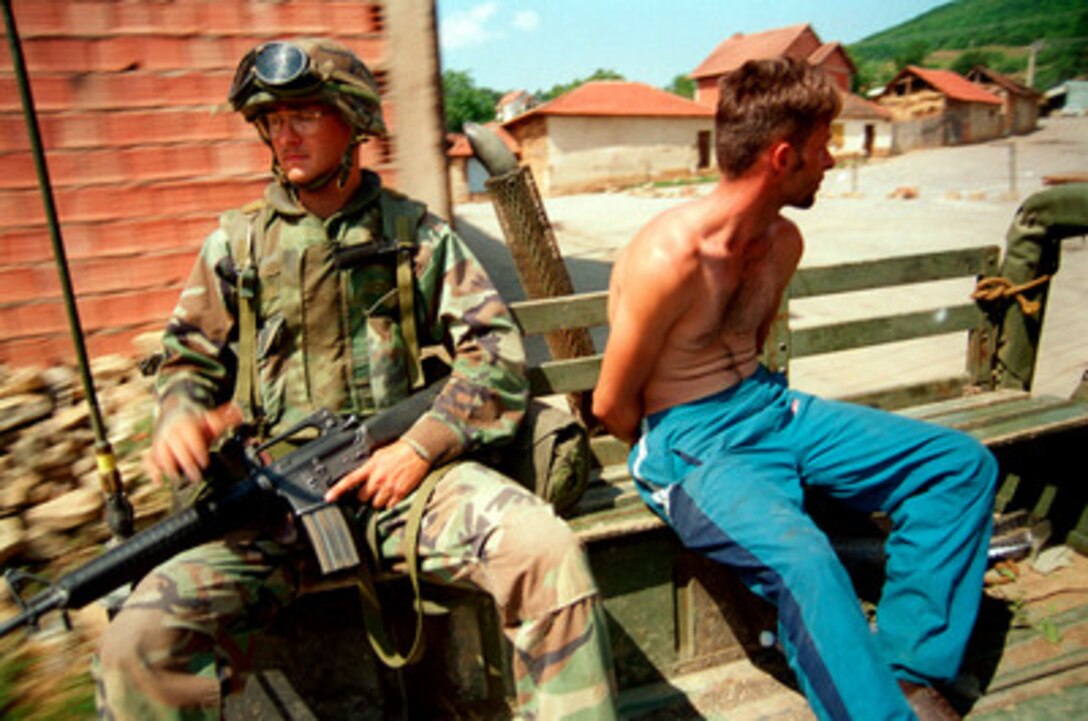 U.S. Marines from Lima Battery, 3rd Battalion, 10th Marine Regiment escort a villager arrested for looting to headquarters for questioning in Zegra, Kosovo, on June 28, 1999. Elements of the 26th Marine Expeditionary Unit are deployed from ships of the USS Kearsarge Amphibious Ready Group as an enabling force for KFOR. KFOR is the NATO-led, international military force which will deploy into Kosovo on a peacekeeping mission known as Operation Joint Guardian. KFOR will ultimately consist of over 50,000 troops from more than 24 contributing nations, including NATO member-states, Partnership for Peace nations and others. 