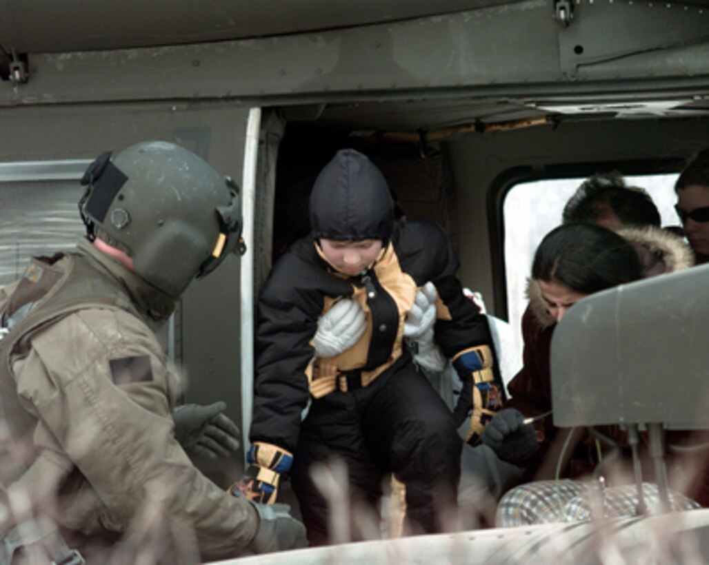 The crew chief of a U.S. Army UH-60 Blackhawk helps a young boy out of the helicopter at the landing zone after being evacuated from an avalanche area in Austria, on Feb. 25, 1999. Blackhawks from the 5th Battalion, 158th Aviation Regiment were sent to Austria to help transport avalanche victims and stranded tourists to safety. 