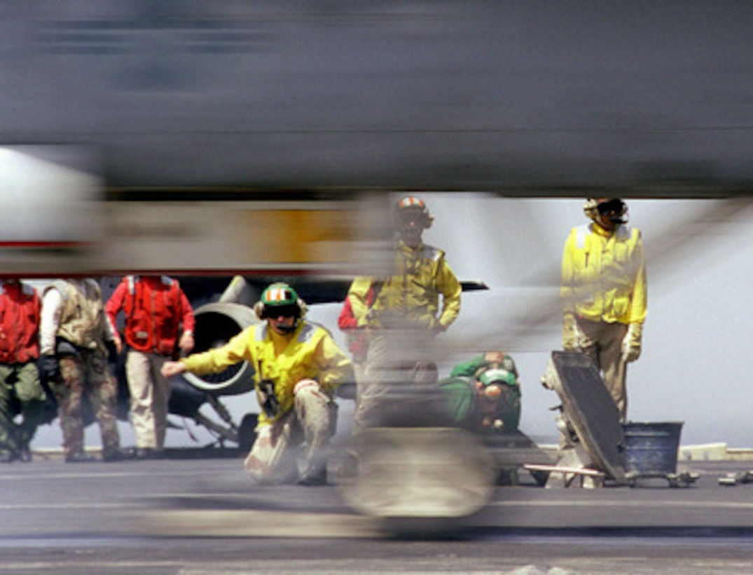 An F/A-18 Hornet becomes a blur in front of the flight deck crew as it is catapulted from the USS Kitty Hawk (CV 63) on May 16, 1999, for an Operation Southern Watch mission. Kitty Hawk and its embarked Carrier Air Wing 5 are on station in the Persian Gulf in support of Southern Watch which is the U.S. and coalition enforcement of the no-fly-zone over Southern Iraq. 