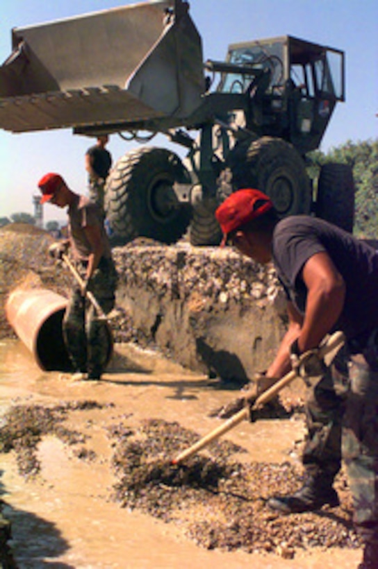 U.S. Air Force Red Horse engineers smooth out a bed of gravel as they lay a pipeline alongside the main road to Rinas Airport at Tiranë, Albania, on May 25, 1999. Red Horse personnel are involved in repairing and enlarging the main road leading out of Rinas Airport in support of Operation Sustain Hope. Sustain Hope is the U.S. effort to bring in food, water, medicine, relief supplies, and to establish camps for the refugees fleeing from the Former Republic of Yugoslavia. Red Horse is a civil engineering unit which deploys heavy equipment quickly to build airfield and support area infrastructure. 