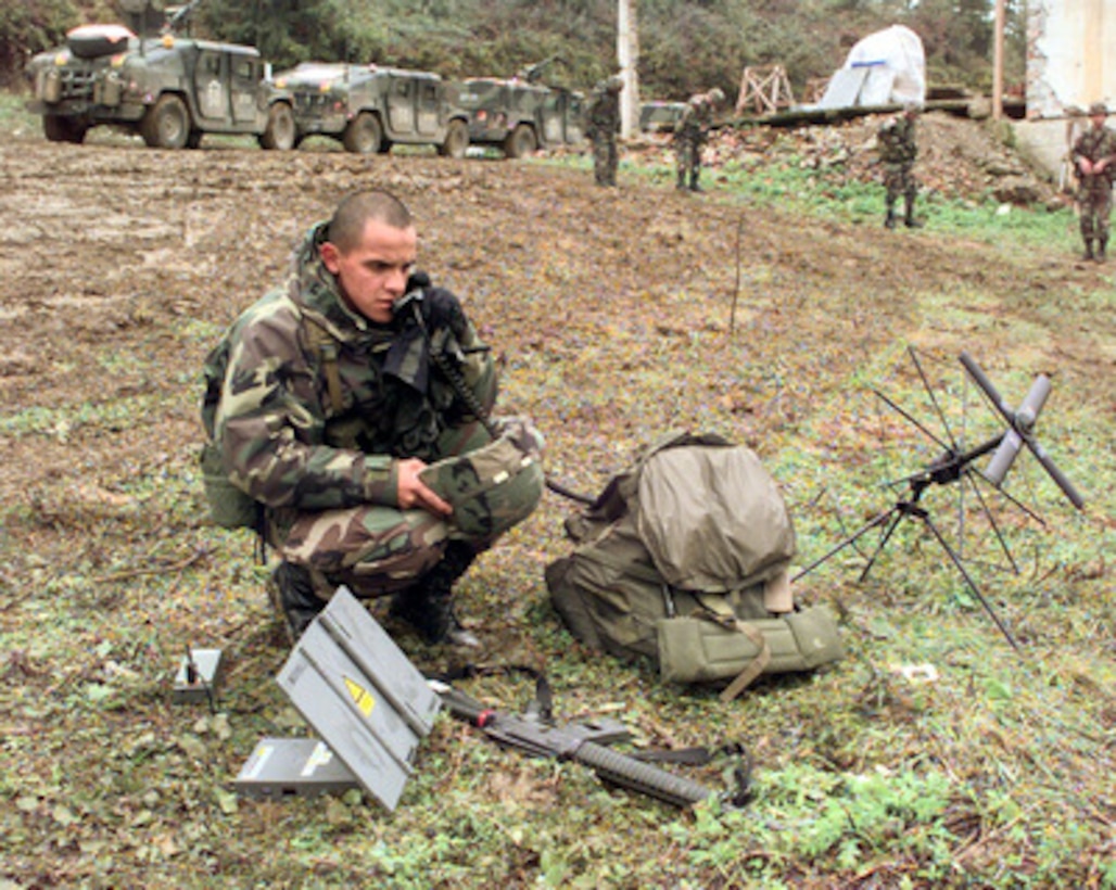 Cpl. Carlos Rivera, U.S. Army, uses a satellite phone to establish communications from the field in the village of Skugrici, Bosnia and Herzegovina, on Oct. 20, 1999. Rivera is the radio operator for the Commander of Multi National Division North and is deployed to Bosnia and Herzegovina in support of Operation Joint Forge. 