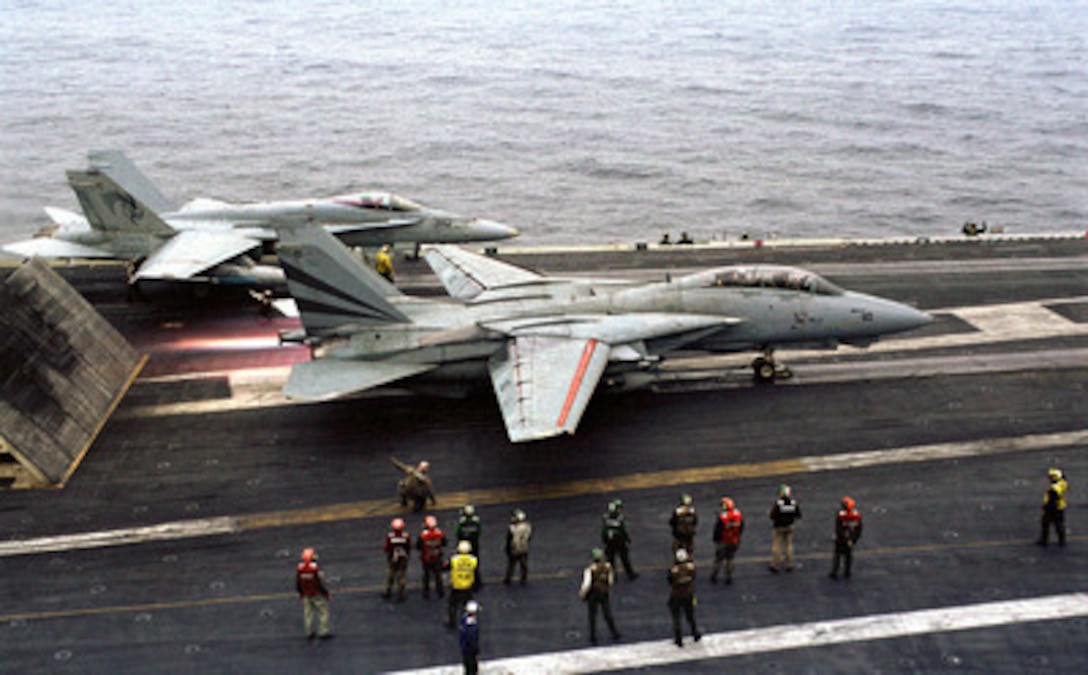 Flight deck personnel watch as an F-14 Tomcat hits the afterburner before launching from the aircraft carrier USS Kitty Hawk (CV 63) during Exercise Foal Eagle '99 on Oct. 31, 1999. The Kitty Hawk (CV 63) and its embarked Carrier Air Wing 5 are participating in Exercise Foal Eagle '99. which is the 38th in a series of regularly scheduled rear area defense field training exercises. The annual exercise is held at a variety of locations throughout the Korean peninsula and involves some 30,000 U.S. military forces. The Tomcat is attached to Fighter Squadron 154. 