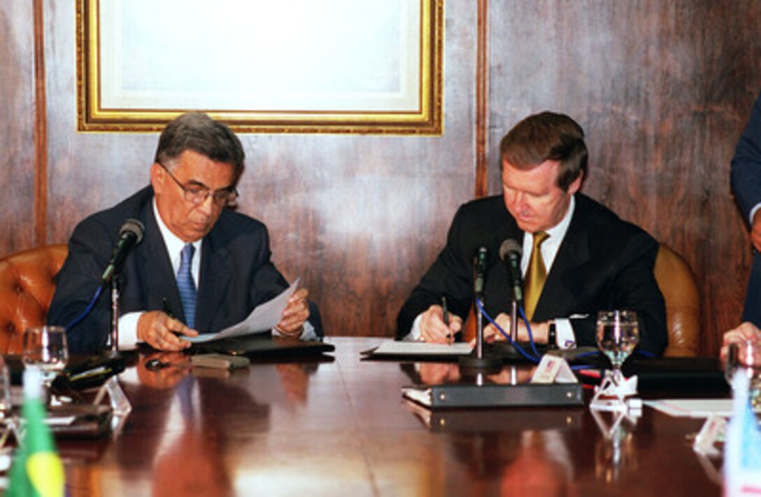 Minister of Defense Elcio Alvares (left) and Secretary of Defense William S. Cohen (right) sign a Bilateral Working Group Agreement on Nov. 12, 1999, at the Ministry of Defense in Brasilia, Brazil. The agreement provides a forum to discuss defense and security issues of mutual interest between the two leaders. The meeting locations will alternate with the first meeting hosted by the U.S. next year. 