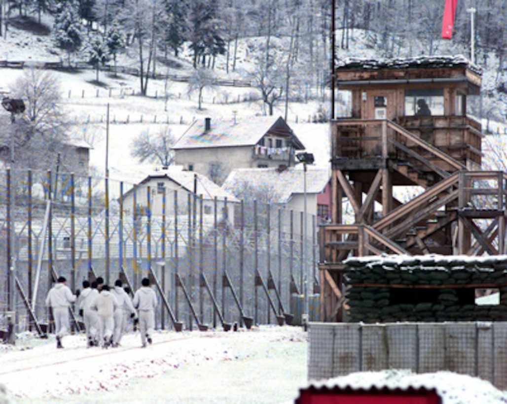Not even a fresh coat of snow will keep soldiers of the U.S. Army's 31st Infantry Regiment from physical fitness training as they run past a guard tower at Camp Demi, Bosnia and Herzegovina, on Nov. 20, 1999. These soldiers from 1st Platoon, A Company, 4th Battalion, are deployed to Bosnia and Herzegovina in support of Operation Joint Forge. 