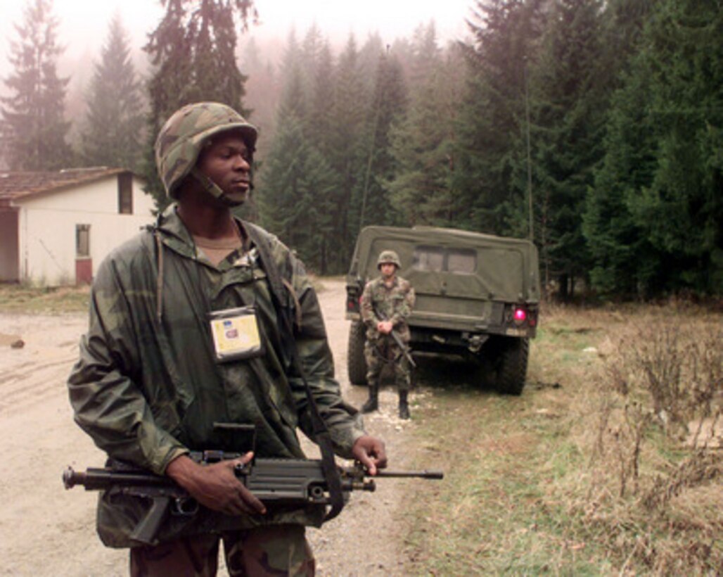 U.S. Army Pfc. Tyce D. James keeps an eye on the woods as he provides security for convoy preparing to leave Hill 1326 in Bosnia and Herzegovina after a resupply mission on Nov. 10, 1999. James is attached to Support Platoon Headquarters of Headquarters Company, 4th Battalion, 31st Infantry Regiment and is deployed to Bosnia and Herzegovina in support of Operation Joint Forge. 