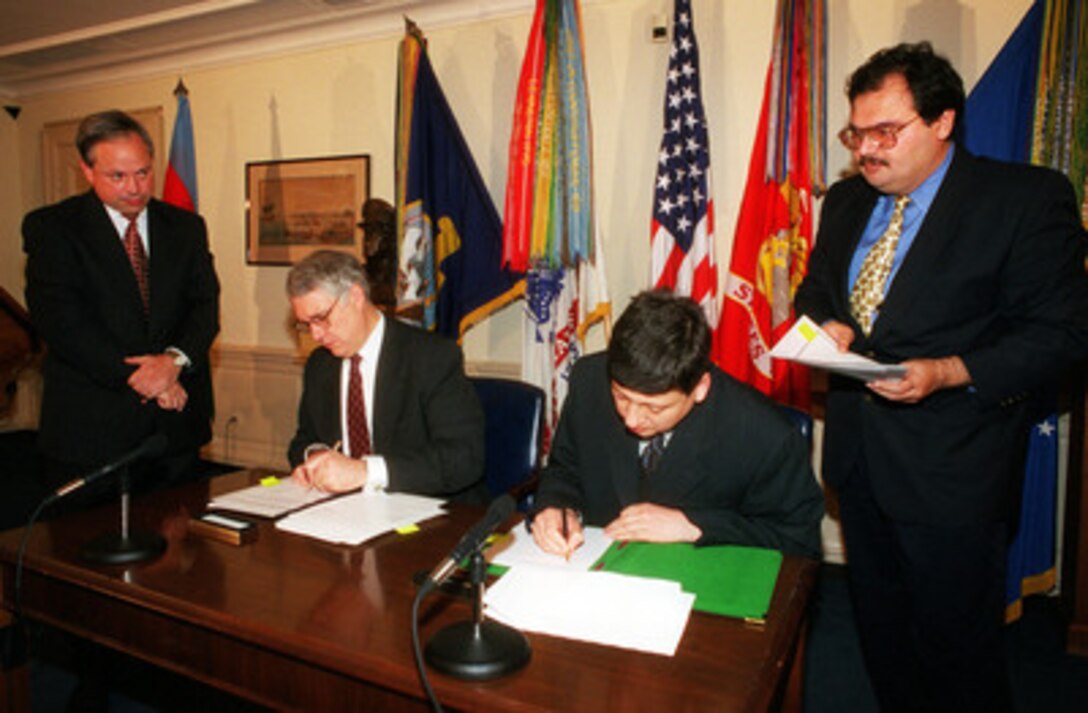 Deputy Secretary of Defense John J. Hamre (seated left) and Minister of Foreign Affairs Tofiq Zulfiqarov of Azerbaijan (seated right), sign an agreement in the Pentagon, on Sept. 27, 1999. The agreeement commits the two nations to cooperate in the area of counter-proliferation of nuclear, chemical, and biological weapons and related materials. 