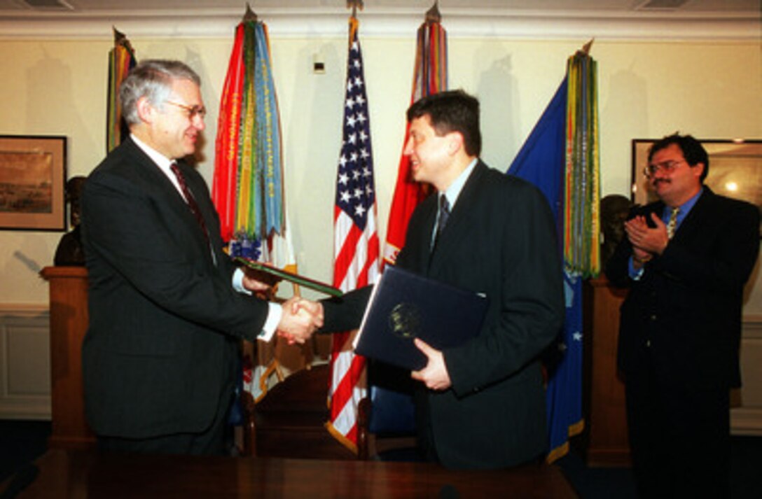 Deputy Secretary of Defense John J. Hamre (left) and Minister of Foreign Affairs Tofiq Zulfiqarov, of the Republic of Azerbaijan, shake hands and exchange copies of the document they just signed in the Pentagon, on Sept. 27, 1999. The agreement commits the two nations to cooperate in the area of counter-proliferation of nuclear, chemical, and biological weapons and related materials. 