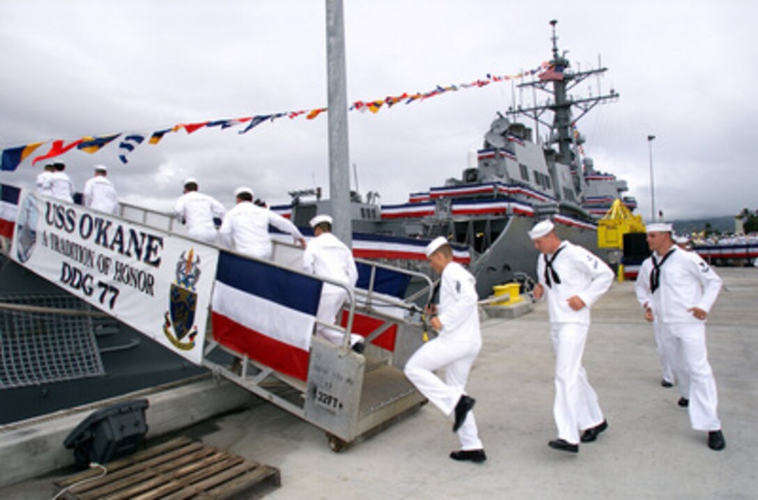 Crew members of the destroyer USS O'Kane (DDG 77) keep with the Navy tradition of running aboard to bring the ship to life during the ship's commissioning ceremony at Naval Station Pearl Harbor, Hawaii, on Oct. 23, 1999. The Arleigh Burke class destroyer is named after Medal of Honor winner Rear Adm. Richard H. O'Kane, commanding officer of the submarine USS Tang during World War II. 
