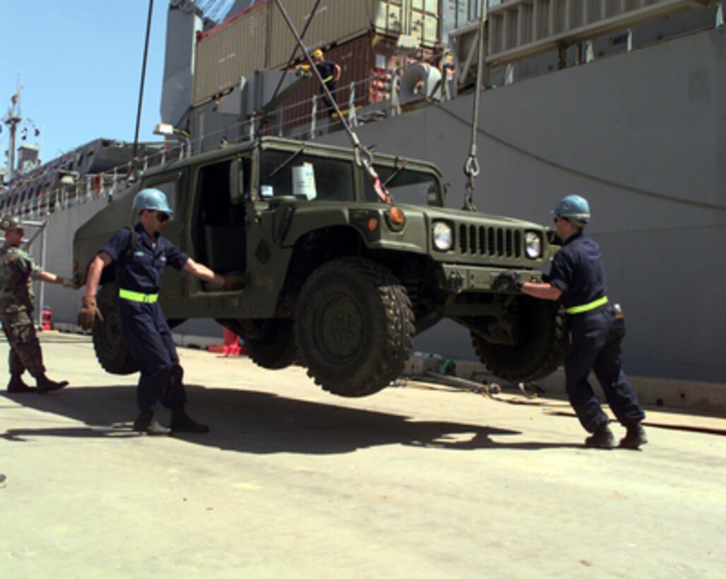 Petty Officer 2nd Class William Hakes, U.S. Navy, grabs the door of a Humvee as Petty Officer 2nd Class Kenneth MacDonald U.S. Navy, grabs the bumper to guide the vehicle to the dock at Gladstone, Australia, on Oct. 9, 1999. Humvees and other light combat vehicles were off-loaded from the Maritime Prepositioning Ship SS Gopher State (T-ACS 4) by crane for Exercise Crocodile '99. Exercise Crocodile '99 is a combined U.S. and Australian military training exercise being conducted at the Shoalwater Bay Training Area in Queensland, Australia. 