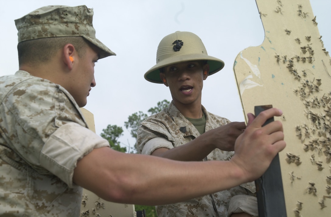 MARINE CORPS BASE CAMP LEJEUNE, N.C. - Sgt. Eric A. Aguilar (right), a PMI with Weapons Training Battalion here instructs Cpl. Thomas Chavez, a Marine Corps Boxing team member, on how get his shots closer in the middle of the target here June 13. The PMIs teach Marines the fundamentals of marksmanship along with weapon safety and weapon handling through annual training before a Marine qualify with his rifle. (Official U.S. Marine Corps photo by Lance Cpl. Brandon R. Holgersen)