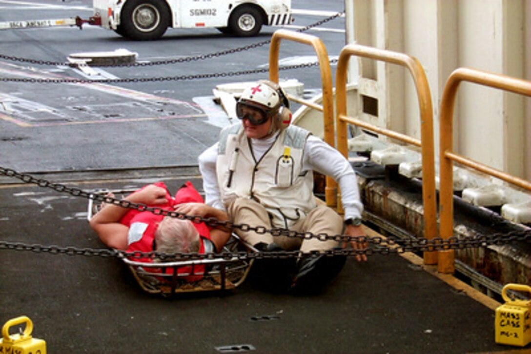 A member of the USS John F. Kennedy (CV 67) medical department monitors an injured crew member rescued from the capsized ocean tug Gulf Majesty as they wait for one of the flight deck elevators to lower them to the medical department on Sept. 15, 1999. Eight crew members were rescued after abandoning their ship in heavy seas off the coast of Florida during Hurricane Floyd. The USS John F. Kennedy responded to their distress call some 150 miles from the tugs reported location. The aircraft carrier had been at sea less than a day after leaving the ship's home port of Mayport, Fla., to ride out Hurricane Floyd. 