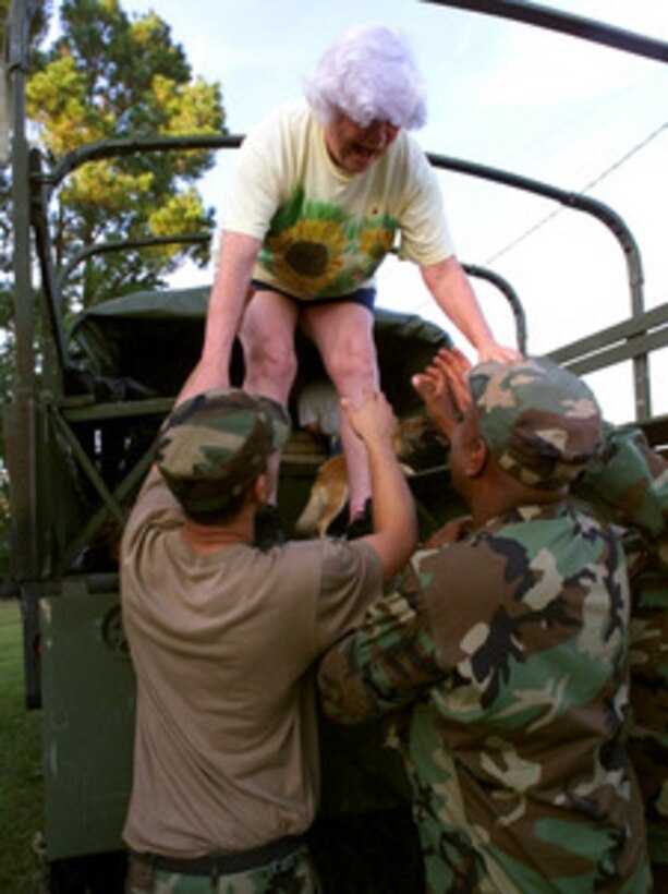 North Carolina National Guard members from Fayetteville and Bladenboro, N.C., help an unidentified woman from a Guard 5-ton military truck near Tick Bite, N.C., on Sept. 18, 1999. The woman was rescued by members of the National Guard from flood waters caused by Hurricane Floyd. Hundreds of National Guard troops in North Carolina and surrounding states been called on state active duty to provide disaster and humanitarian relief for thousands of people hit by Hurricane Floyd. 