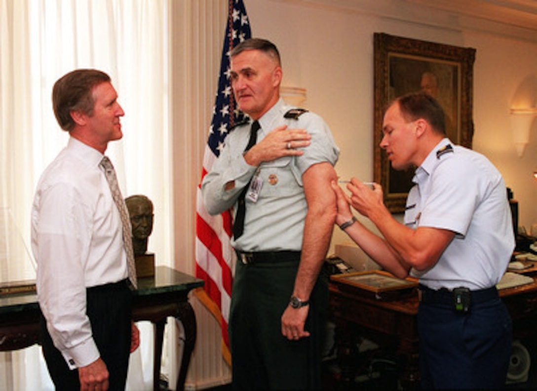 U.S. Air Force Flight Surgeon Maj. Timothy Ballard (right) administers the final shot in the six-dose series of anthrax inoculations to Chairman of the Joint Chiefs of Staff Gen. Henry Shelton (center), U.S. Army, as Secretary of Defense William S. Cohen (left) watches in the Pentagon on Sept. 24, 1999. Following this shot, a once-a-year booster is all that will be required to maintain resistance to anthrax. Ballard is attached to the 11th Medical Group. 
