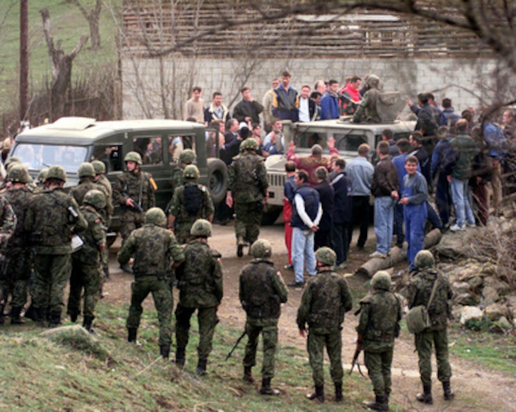 A Military Police squad from the 709th Military Police Battalion crosses a bridge in Sevce, Kosovo, where several hundred Kosovar Serbs were blocking the road on April 4, 2000. The crowd gathered to protest the arrest earlier in the day of a local who was suspected of possesing munitions. 