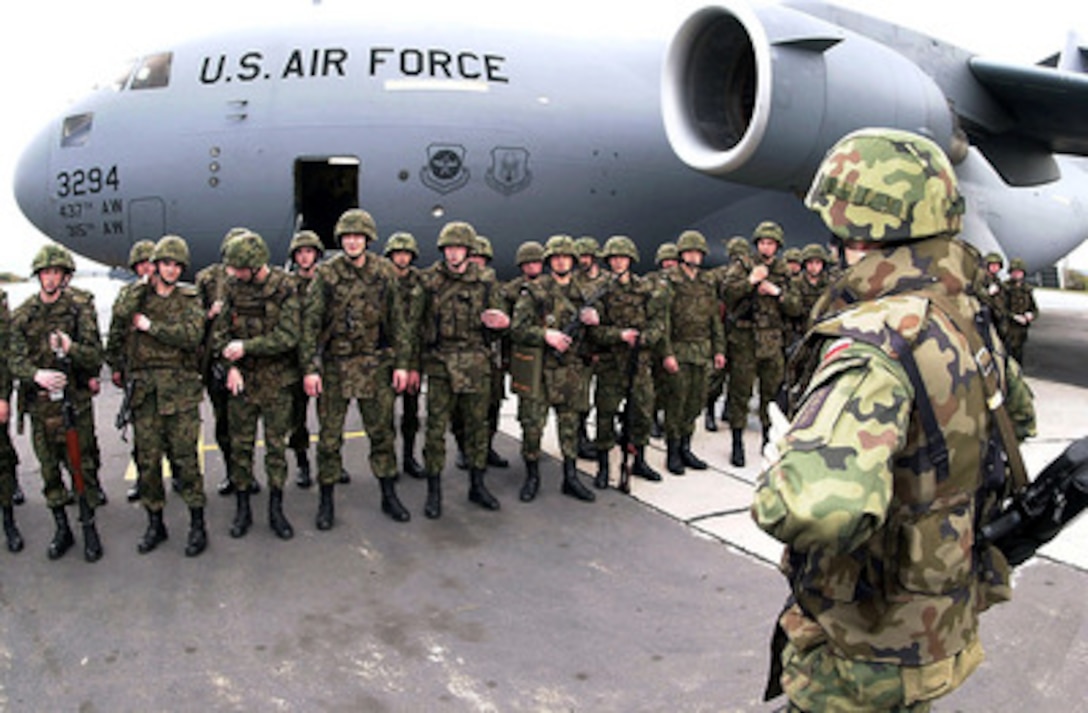 Soldiers from the 10th Polish Infantry Battalion wait in formation before boarding a U.S. Air Force C-17 Globemaster III at Ramstein Air Base, Germany, on April 21, 2000. The Globemaster is airlifting the troops to Kosovo as part of a reserve force being deployed to Mitrovica to augment KFOR, the NATO peacekeeping mission. The Globemaster is deployed from Charleston Air Force Base, S.C. 