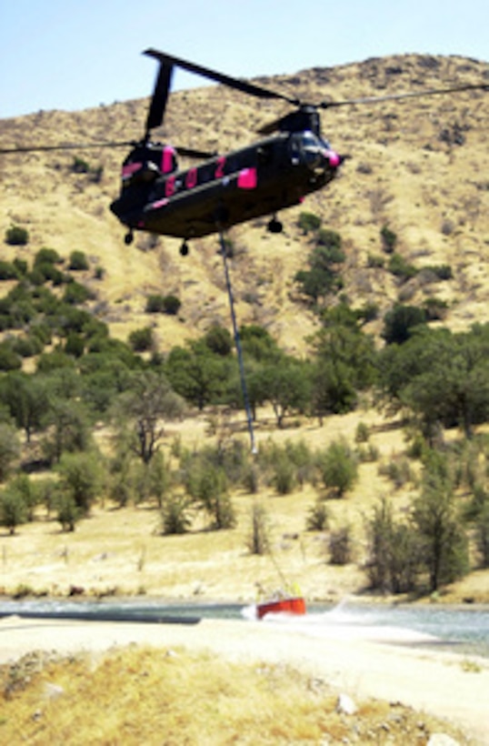 A California Army National Guard CH-47 Chinook helicopter wrenches a 660-gallon water bucket out of an aqueduct to deposit water on fires still smoldering in the Sequoia National Forest near Kernville, Calif. on Aug. 8, 2000. More than 2,300 servicemembers from the Army, Marines, Air and Army Guard and Air Force Reserve are conducting firefighting and support operations for the Western wildfires in response to requests from the National Interagency Firefighting Center in Boise, Idaho, and as directed by the governors of several states. The Chinook and its crew are attached to Company G, 3rd Battalion, 140th Aviation based in Stockton, Calif. 