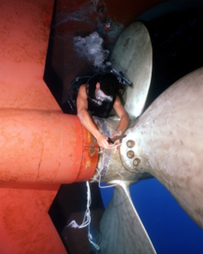 Navy Diver Petty Officer 2nd Class Benjamins uses his dive knife to cut away heavy gauge fishing line to free the fouled propeller of the USS Grasp (ARS 51) in the Mediterranean Sea on June 15, 2000. Benjamins, a Navy electrician's mate, discovered the fishing line during a routine inspection of Grasp's hull and running gear. The Grasp is a Safeguard class salvage ship home ported in Little Creek, Va. 