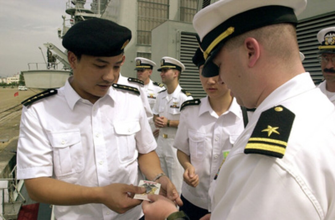 U.S. Navy Lt. j.g. Bruce Sutherland (right) gives Capt. Wen Hai Wu (left), of the People's Liberation Army (Navy), a U.S. Navy officer's crest as a token of appreciation and goodwill during the port visit of the USS Chancellorsville (CG 62) to Qingdao, China, on Aug. 3, 2000. Wu and other crew members of the Chinese warship Haerbin (DDG 112) are exchanging visits with the crew of the Chancellorsville while the Ticonderoga class, Aegis guided missile cruiser visits Qingdao. 